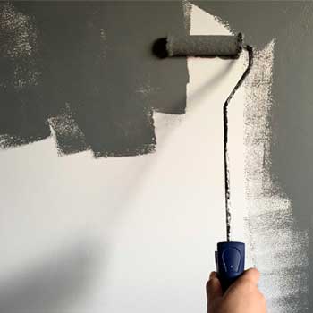 Person holding paint roller while painting the wall